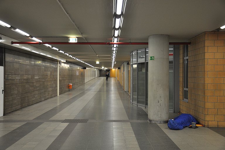 Zwischengeschoss des Nürnberger Bahnhofes, eine Person schläft im Schlafsack