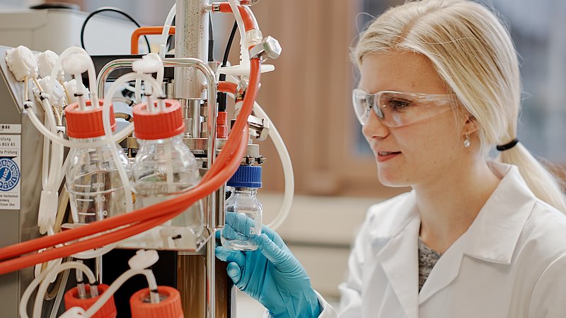 A student takes a sample from a bioreactor